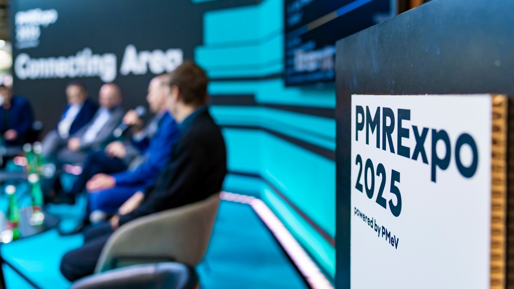 Eine Impulsdiskussion auf der PMRExpo 2025, bei der mehrere Sprecher vor einem lebhaften Hintergrund mit Veranstaltungsbranding zu sehen sind.