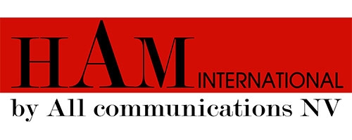 Das Bild zeigt das Logo von HAM International durch All Communications NV, wobei der Name prominent in fetten Buchstaben auf einem roten Hintergrund hervorgehoben wird, passend zur Präsentation neuester Produkte und Lösungen für GSM-Innenraumabdeckung auf der PMRExpo.