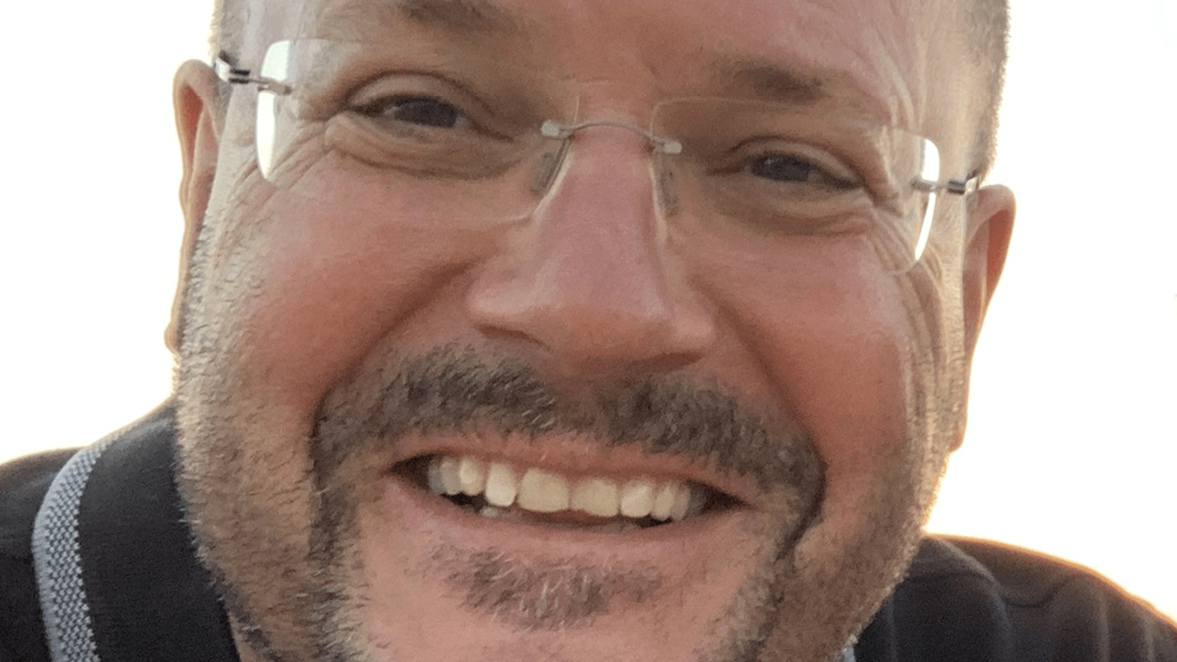 Ein lächelnder Mann mit Brille und kurzem Haar, der einen Bart trägt und ein dunkles Hemd anhat, steht in einer nahen Aufnahme vor einem hellen Hintergrund und vermittelt die Begeisterung von Kristof Speer, dem geschäftsführenden Gesellschafter der NoraTec GmbH, für die PMRExpo und die Präsentation der Software DIASweb.